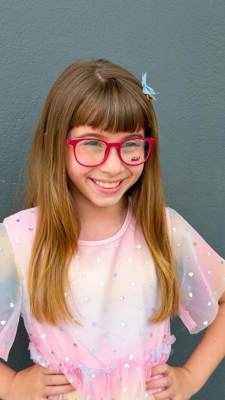 Menina sorrindo com óculos de grau rosa